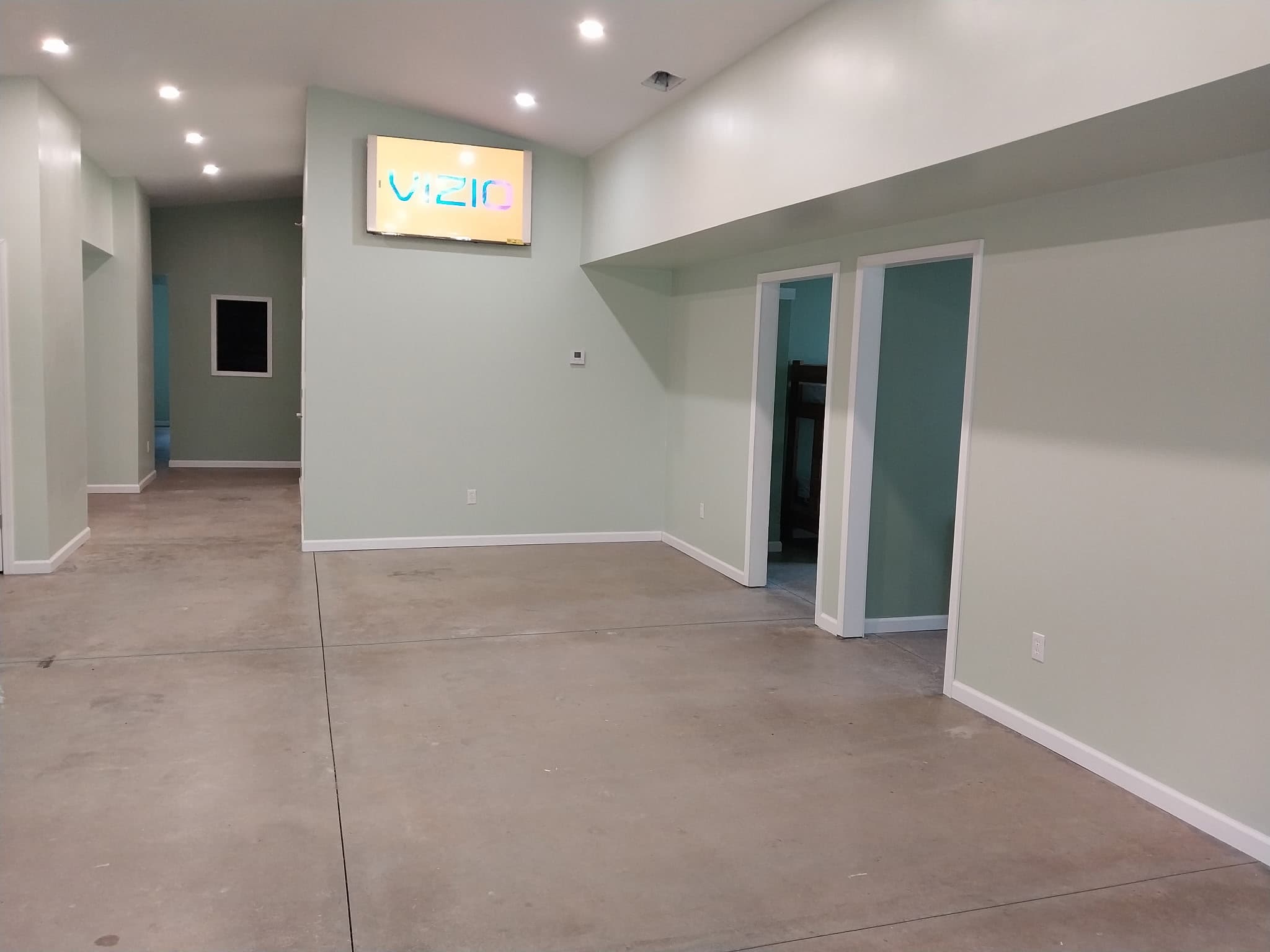 Open common area with sage-green walls and recessed lighting