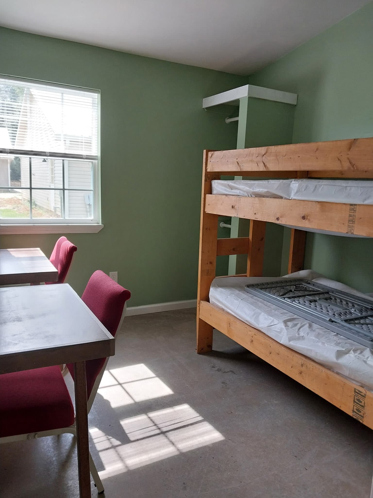 Bunk room with sage-green walls and study table at Camp Legacy