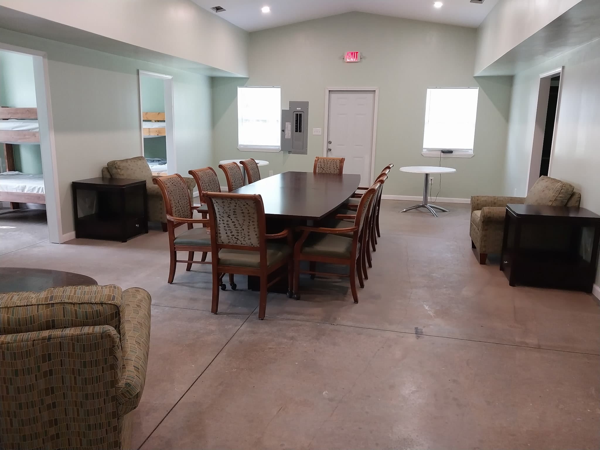 Common room with dining table and bunk rooms beyond at Camp Legacy