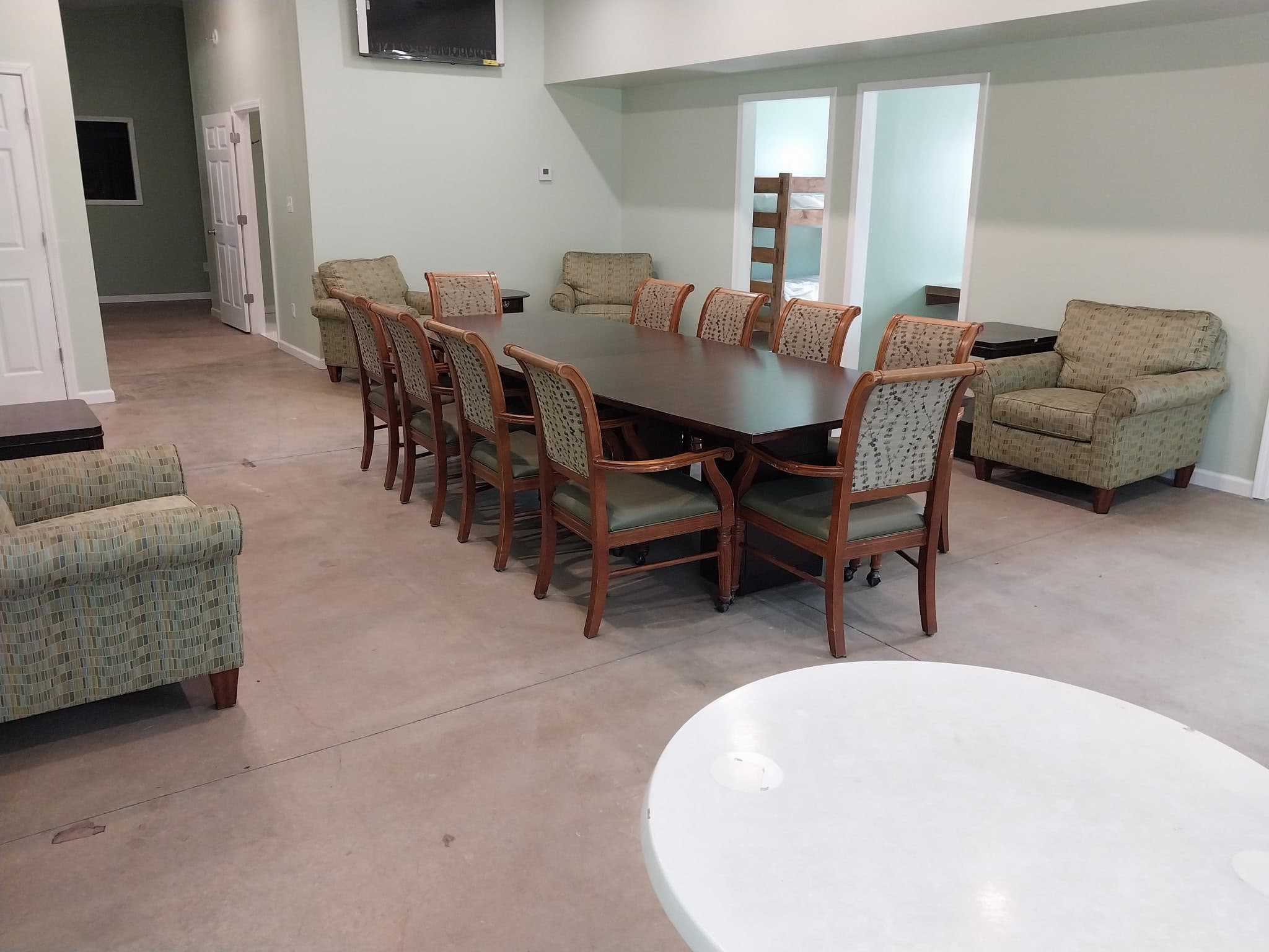 Gathering space with table, upholstered chairs, and sofas at Camp Legacy