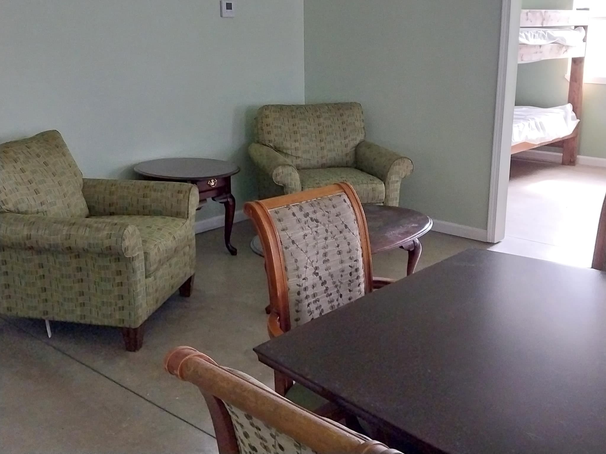 Lounge with armchairs and bunk room beyond at Camp Legacy